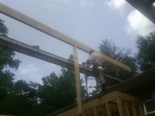 Carpenter setting a ridge beam over a new addition frame — Ice Dam Removal by Roofing Brothers in Baldwin
