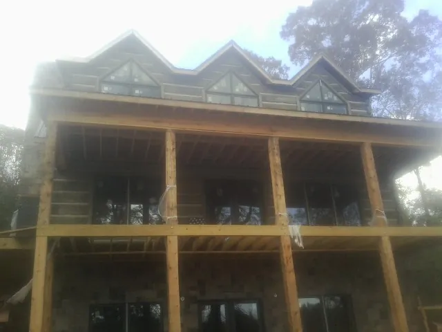 Dormers and porch framing on a large log home under construction — Roof Coating work by our crew in Baldwin