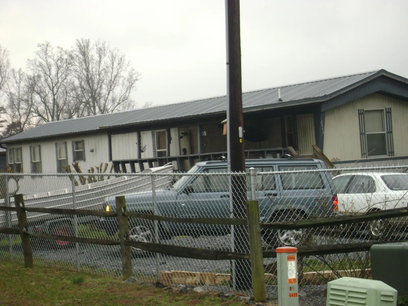 Dark metal roof on a long single story building behind a chain link fence in Baldwin